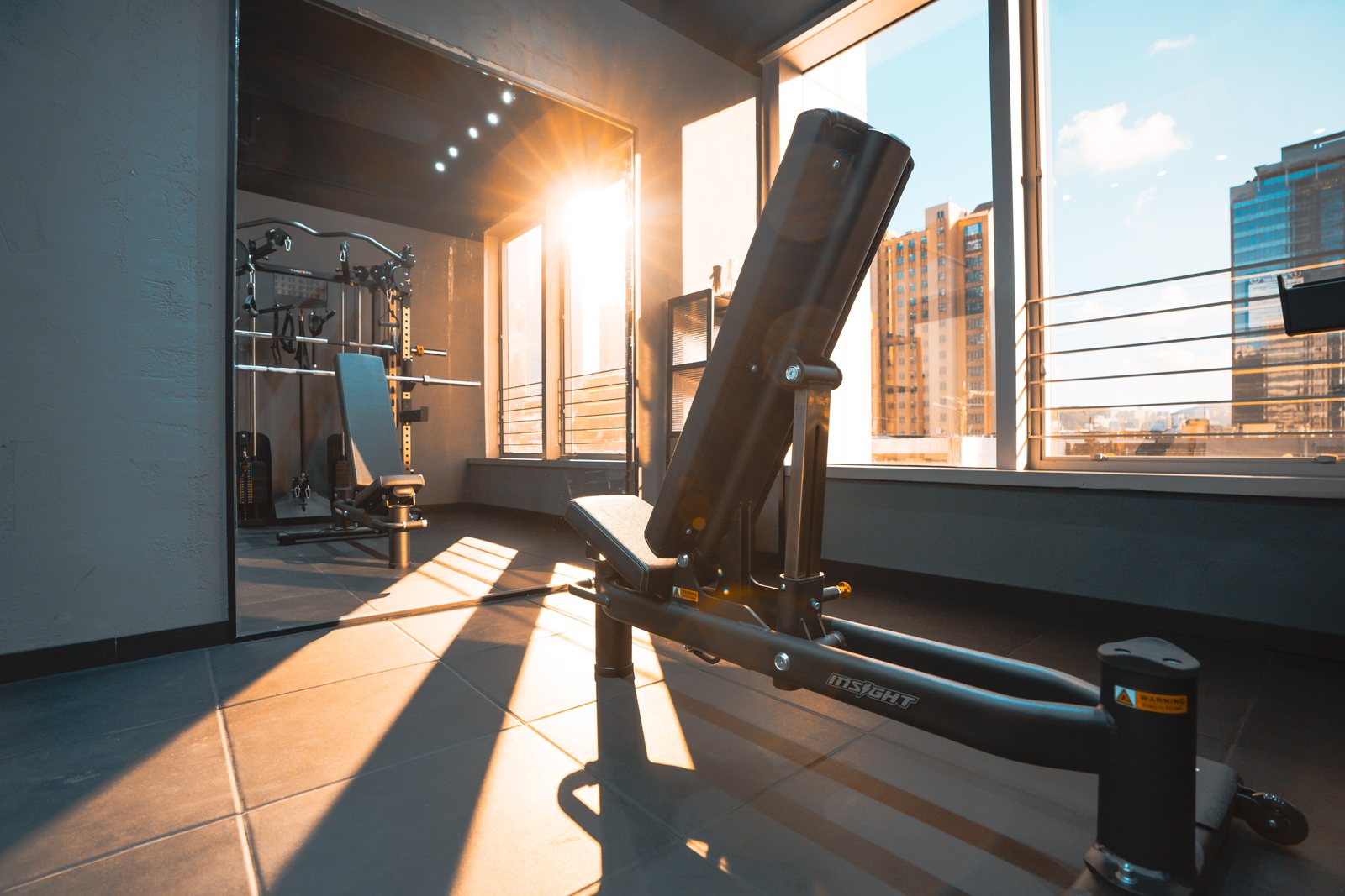 陽光照進 HOMEGYM 房間，畫面可見訓練椅及多功能訓練架